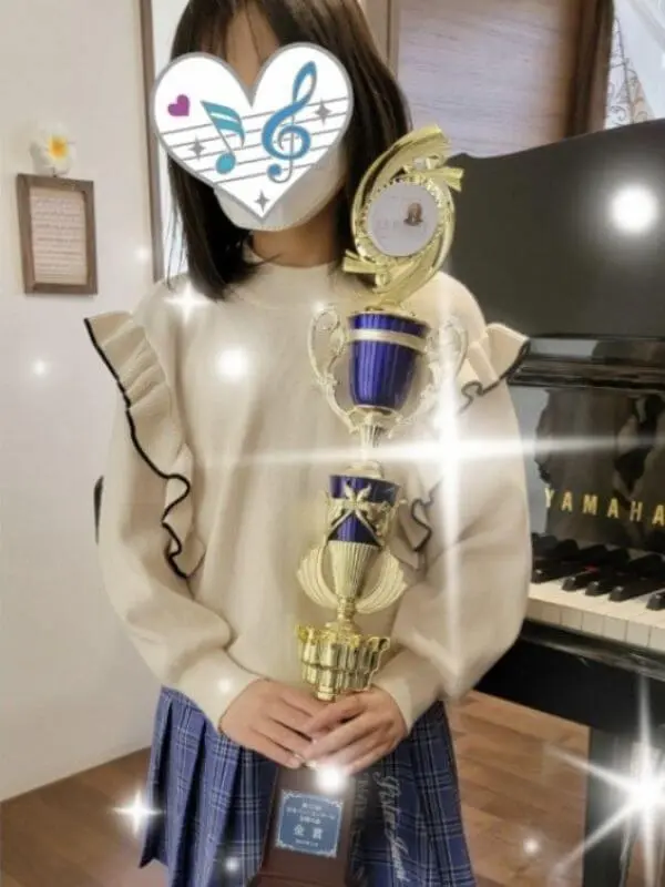N piano music schoolの生徒が、ピアノコンクールで金賞を受賞し特大トロフィーを持つ姿(小山市)