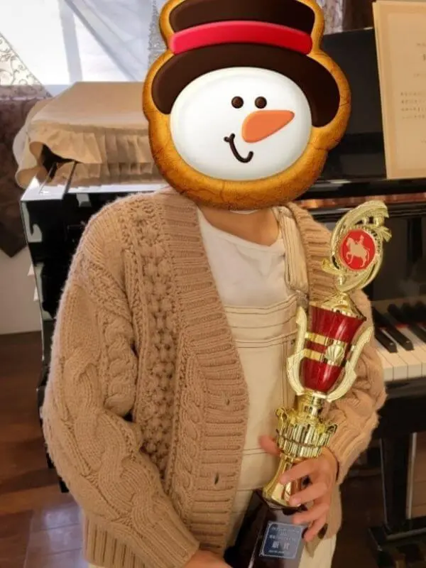ブルグミュラーコンクールで銀賞を受賞したN piano music schoolのKちゃん。トロフィーを手に嬉しそうな様子。