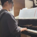 卒業式のピアノ伴奏に向けて練習しているN piano music schoolの生徒の後ろ姿