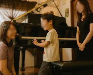 N piano music schoolの体験レッスンで講師と保護者と向き合う子ども。グランドピアノと温かい雰囲気の教室の様子。