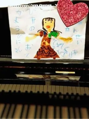 N piano music schoolの生徒が講師に贈った手描きのメッセージイラスト。ピアノの上に飾られた、感謝の気持ちが込められた心温まる絵。