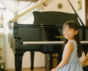 グランドピアノの前に座る小さな女の子。レッスン前の静かなひととき