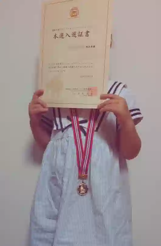 小山市のピアノ教室 N piano music school に通う小学生の生徒が、ピティナ・ピアノコンペティション本選入選証書とメダルを持っている様子。