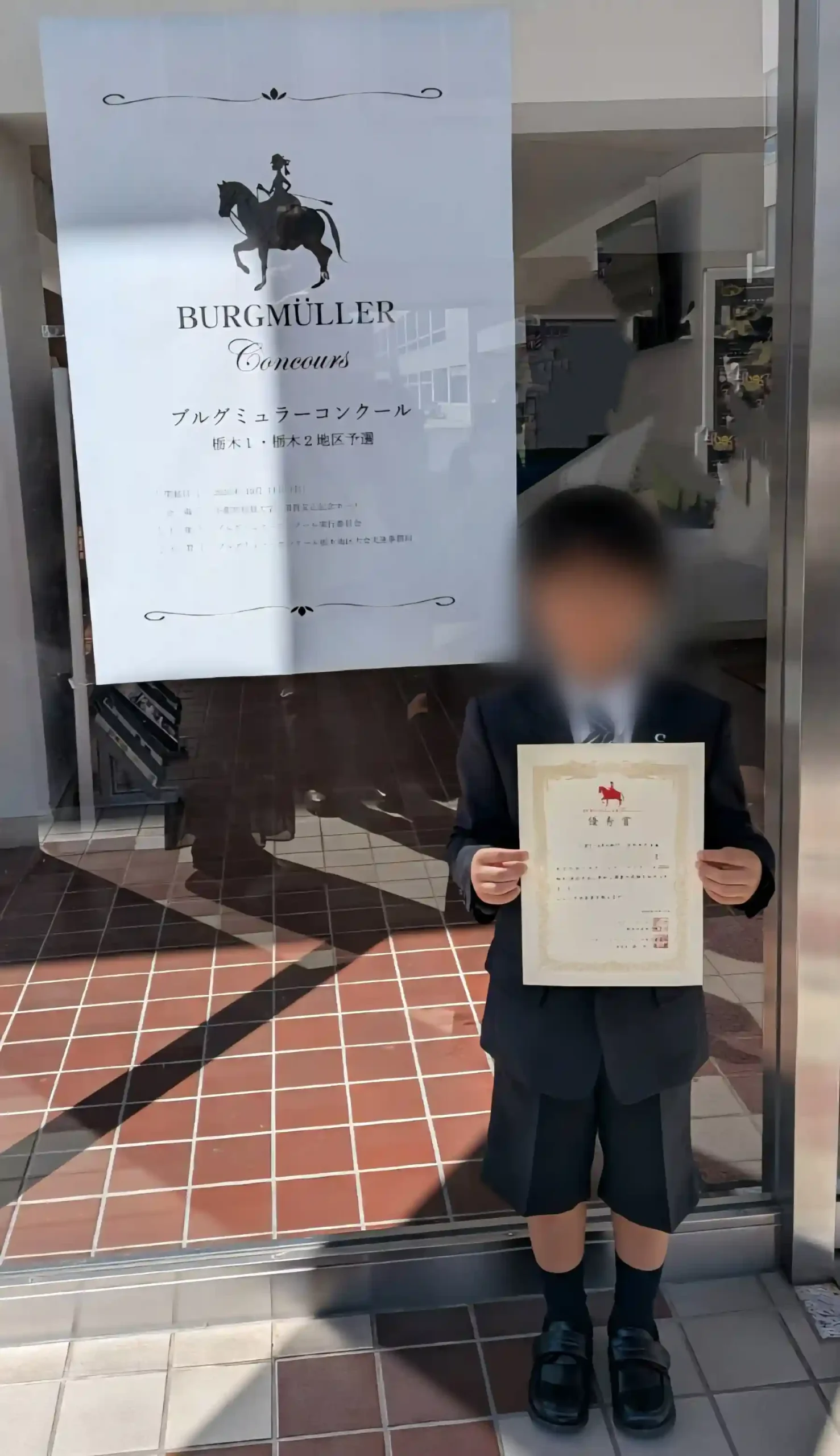 小山市のピアノ教室N piano music schoolの生徒が、ブルグミュラーコンクールに参加し、優秀賞を受賞。嬉しそうに賞状を持つ男の子の様子が収められている写真
